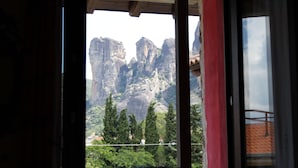 A view through a window with a red frame, revealing a mountainous landscape with rocky formations and greenery. - Guesthouse Monastiri (Kalabaka)