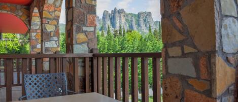 Un balcon aux murs de pierre offrant une vue sur des formations rocheuses et une végétation luxuriante.