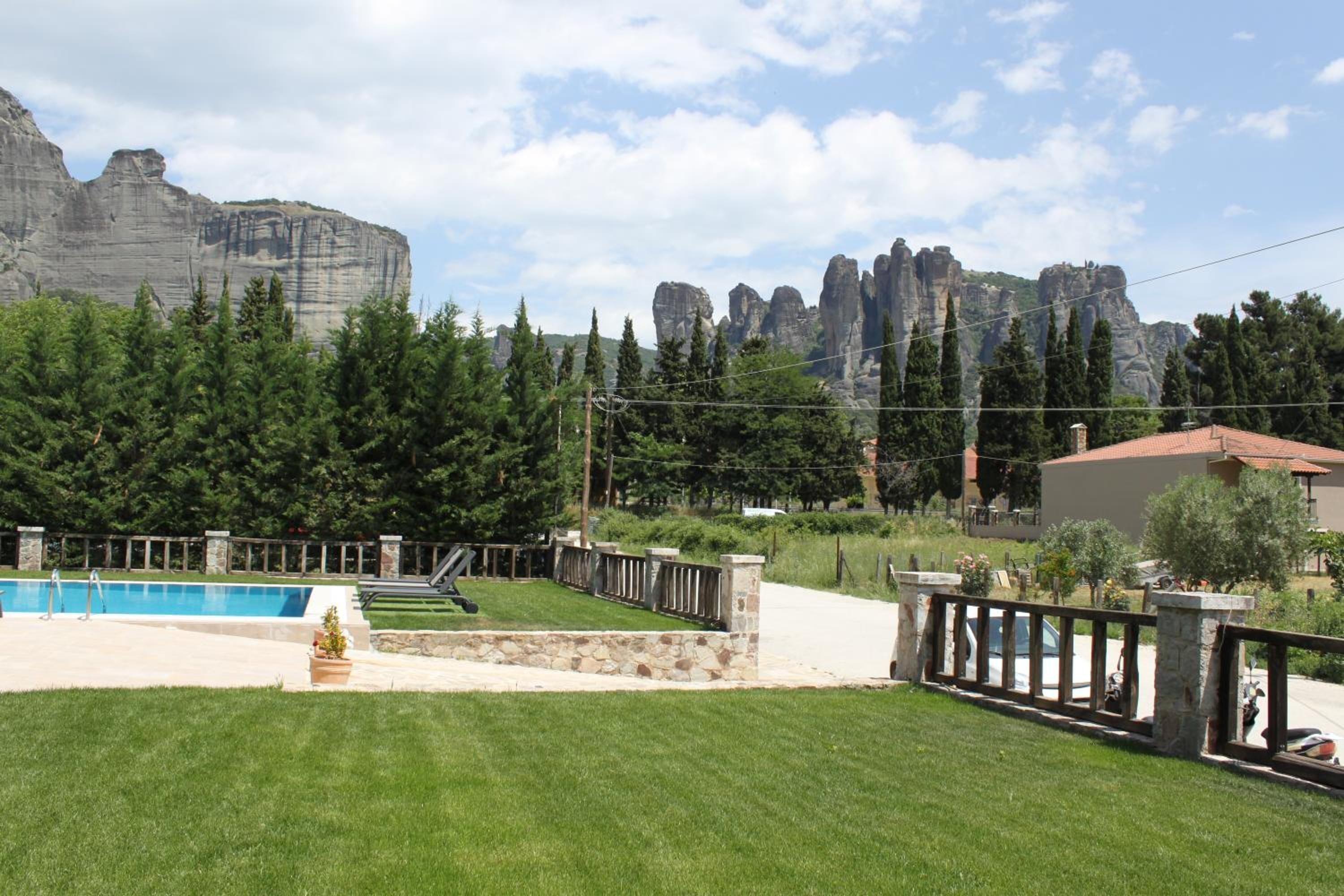 Una piscina con borde de piedra, rodeada por un césped cuidado y una valla de piedra.