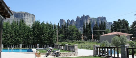A residential area with a swimming pool, a parked scooter, and a view of mountain peaks.