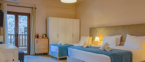 A hotel room with two beds, a desk, a wardrobe, and a balcony with a view.