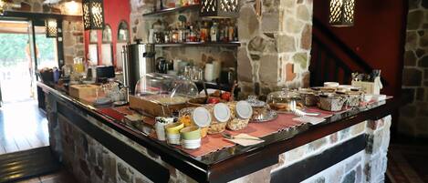 A breakfast bar with a stone wall backdrop, a coffee station, and hanging lanterns.