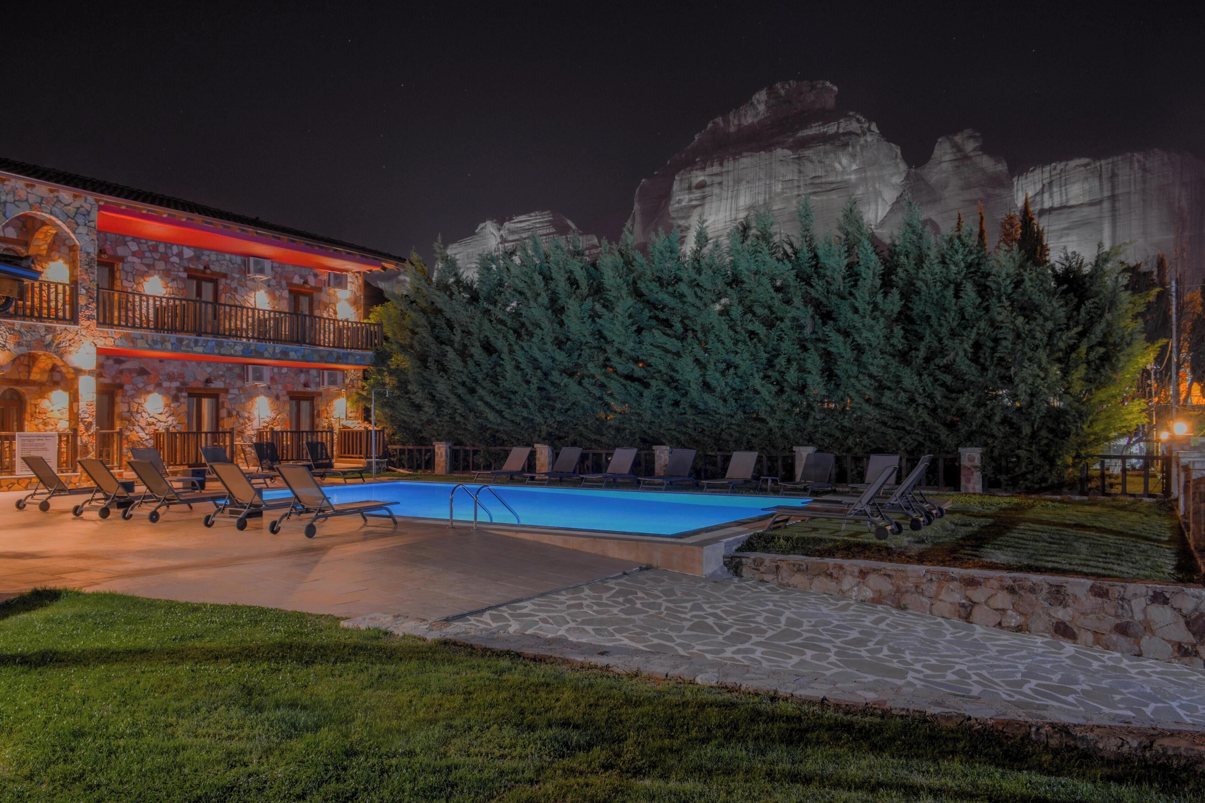 A hotel with a swimming pool, outdoor seating, and a view of rock formations.