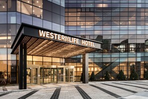 The Western Life Hotel entrance with a modern glass facade, a revolving door, and a covered entrance area. - WesternLife Hotel (Iksan)