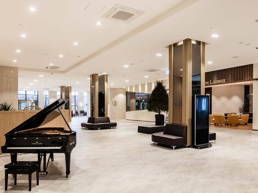 Ein Flügel in einer geräumigen Lobby mit moderner Sitzgelegenheit und einem Empfangsbereich.