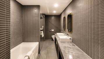 A modern bathroom with a bathtub, two sinks, and a large mirror.
