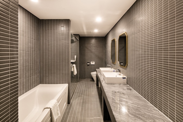 Un baño moderno con una bañera, dos lavamanos y un espejo grande.