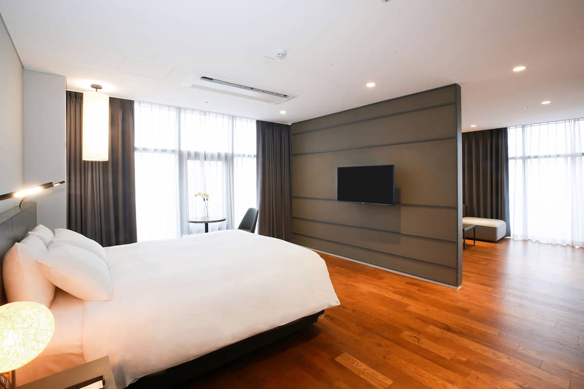 Ein modernes Hotelzimmer mit einem großen Bett, einem flachbildfernseher an der Wand und Holzboden.