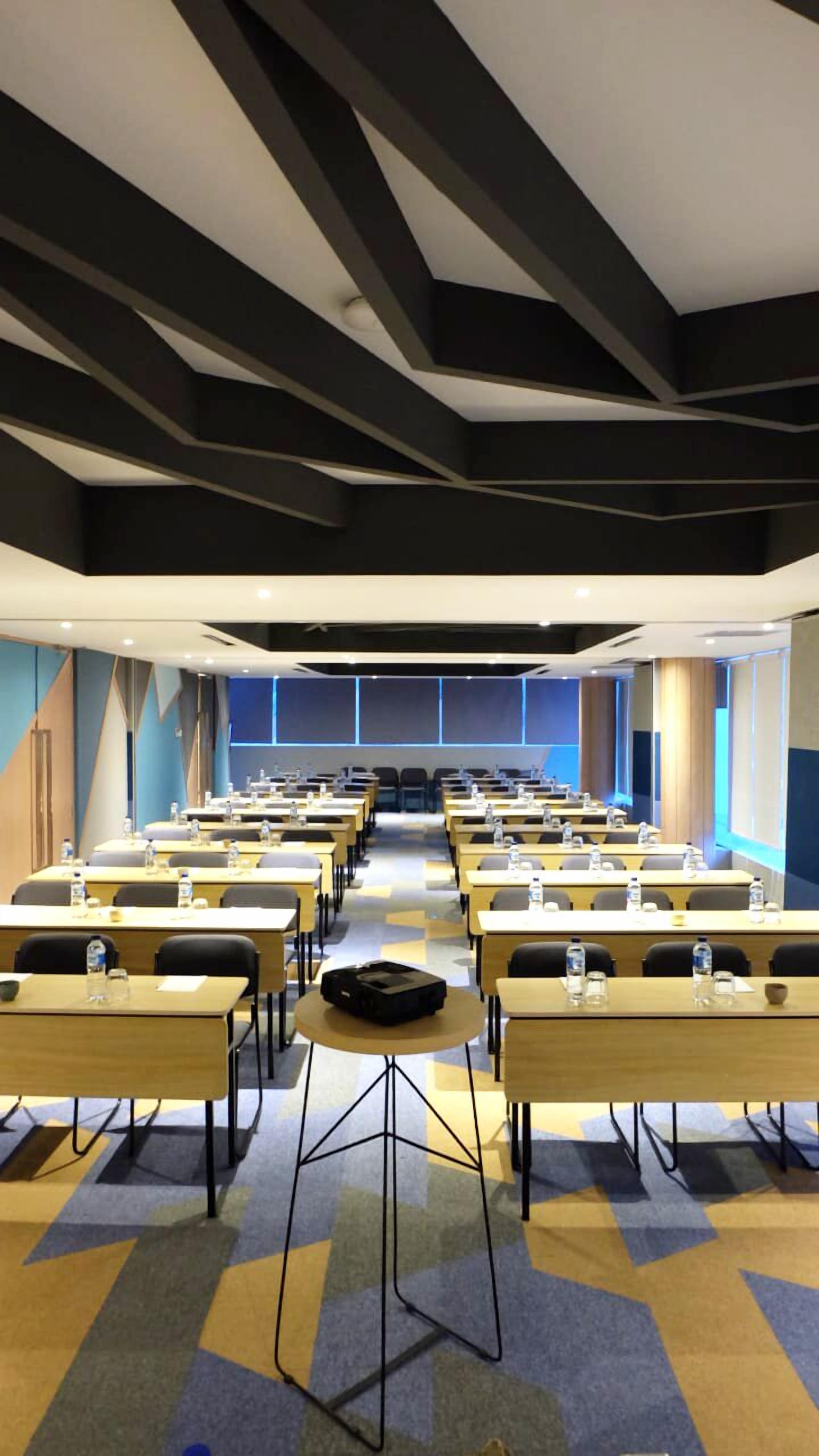 A conference room with rows of tables, chairs, and a podium at the front.