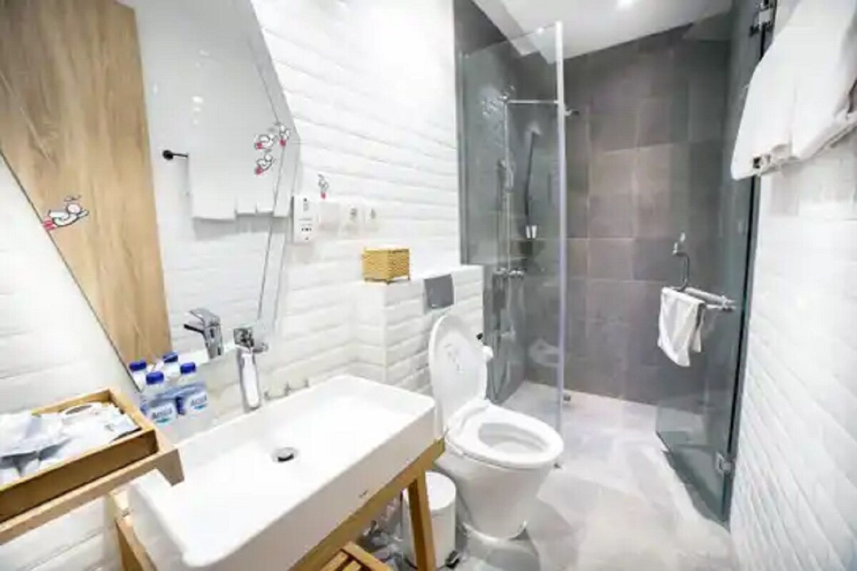A modern bathroom with a glass-enclosed shower, a white sink, and a toilet.