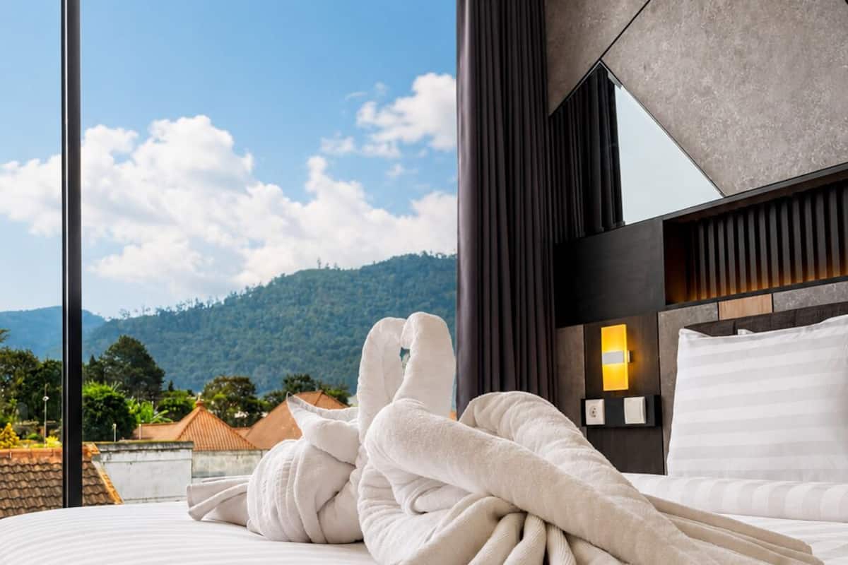 A hotel room with a large bed, a view of the mountains, and a modern design.