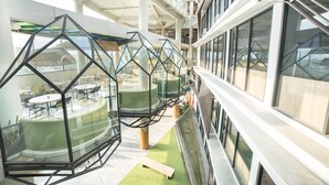 Un interior moderno con zonas de estar con paredes de vidrio y un espacio verde central.