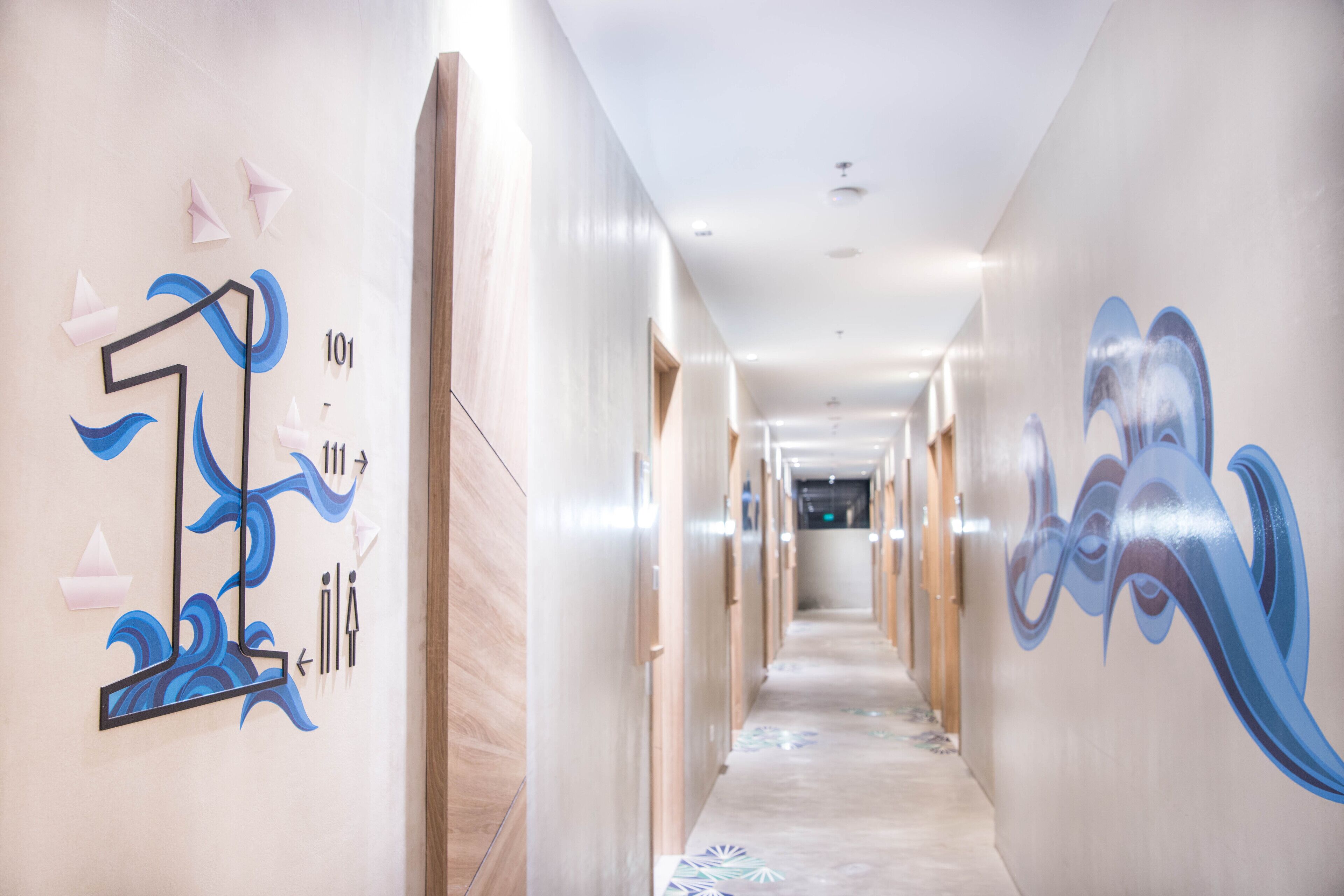 A hotel hallway with a long corridor, doors on both sides, and artistic wall decorations.