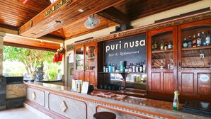 A bar area with wooden cabinets, a sign reading "puri nusa bar & restaurant," and a fan on the ceiling. - Puri Nusa Beach Hotel (Lembongan Island)