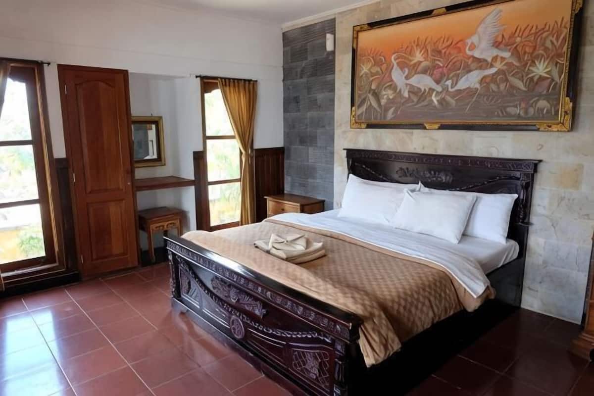Une chambre Ă coucher avec un grand lit, une table de chevet, une commode et un tableau au mur.