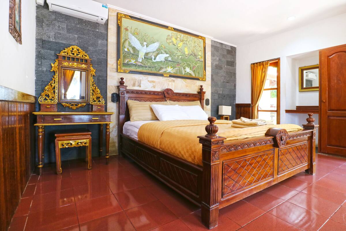 Un dormitorio con cama de madera, una mesita de noche, cómoda, espejo y un cuadro en la pared.