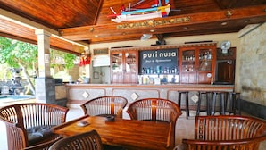 A wooden bar area with a sign reading "puri nusa Bar & Restaurant," surrounded by wooden chairs and tables. - Puri Nusa Beach Hotel (Lembongan Island)