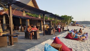 An outdoor seating area with wicker furniture and a covered patio. - Puri Nusa Beach Hotel (Lembongan Island)