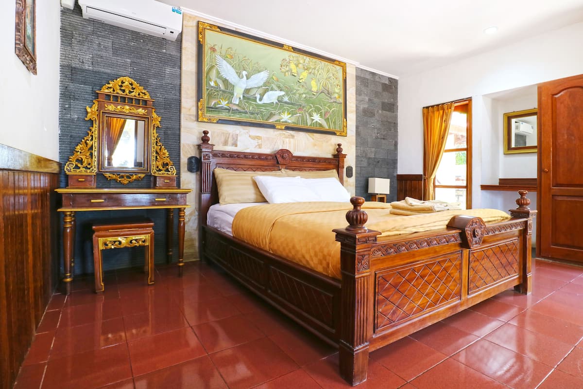 Un dormitorio con cama de madera, un espejo, una mesita y un cuadro en la pared.