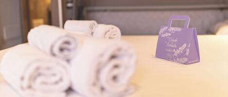 A neatly arranged set of rolled towels and a purple gift bag on a table.