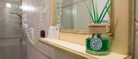 A bathroom with a mirror, a shelf, and a bottle of Mare ambient perfume.