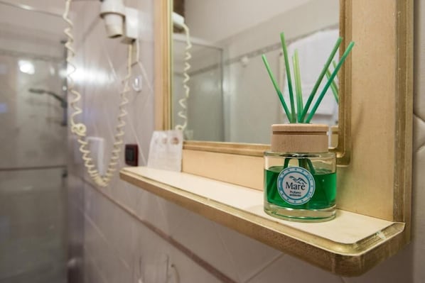 Un baño con espejo, repisa y una botella de perfume ambientador Mare.