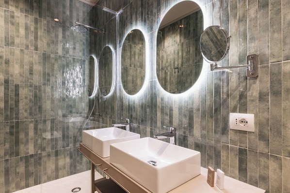 A modern bathroom with two sinks, a shower, and three mirrors.
