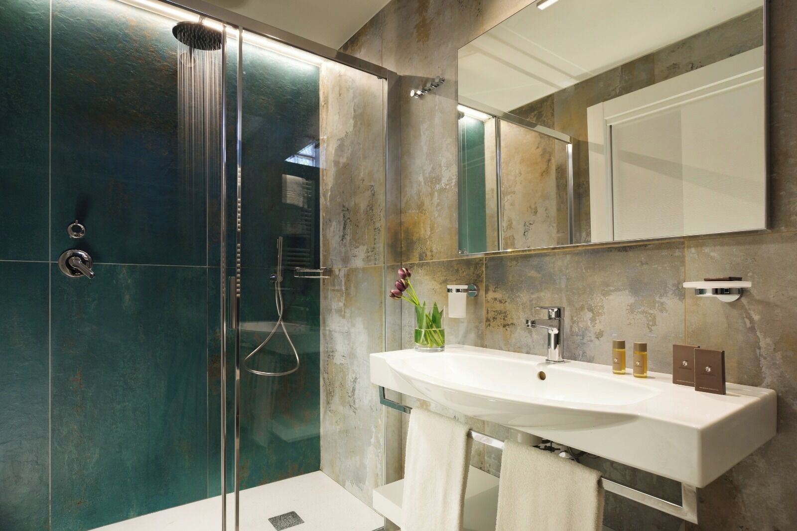 Une salle de bain moderne avec une douche à parois de verre, un lavabo blanc et un grand miroir.