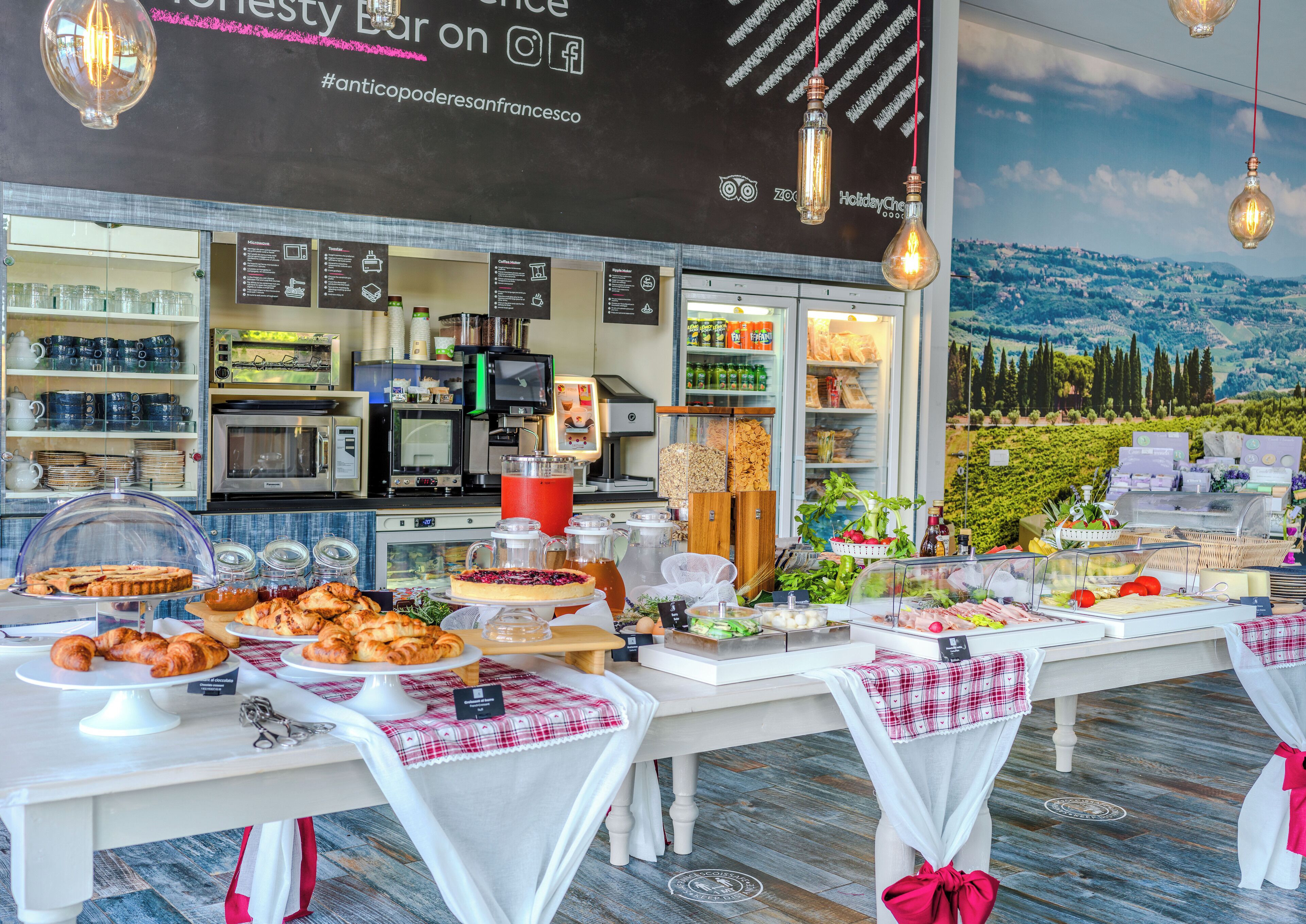 Una cafetería con una máquina de café, vitrinas y vistas a un viñedo.