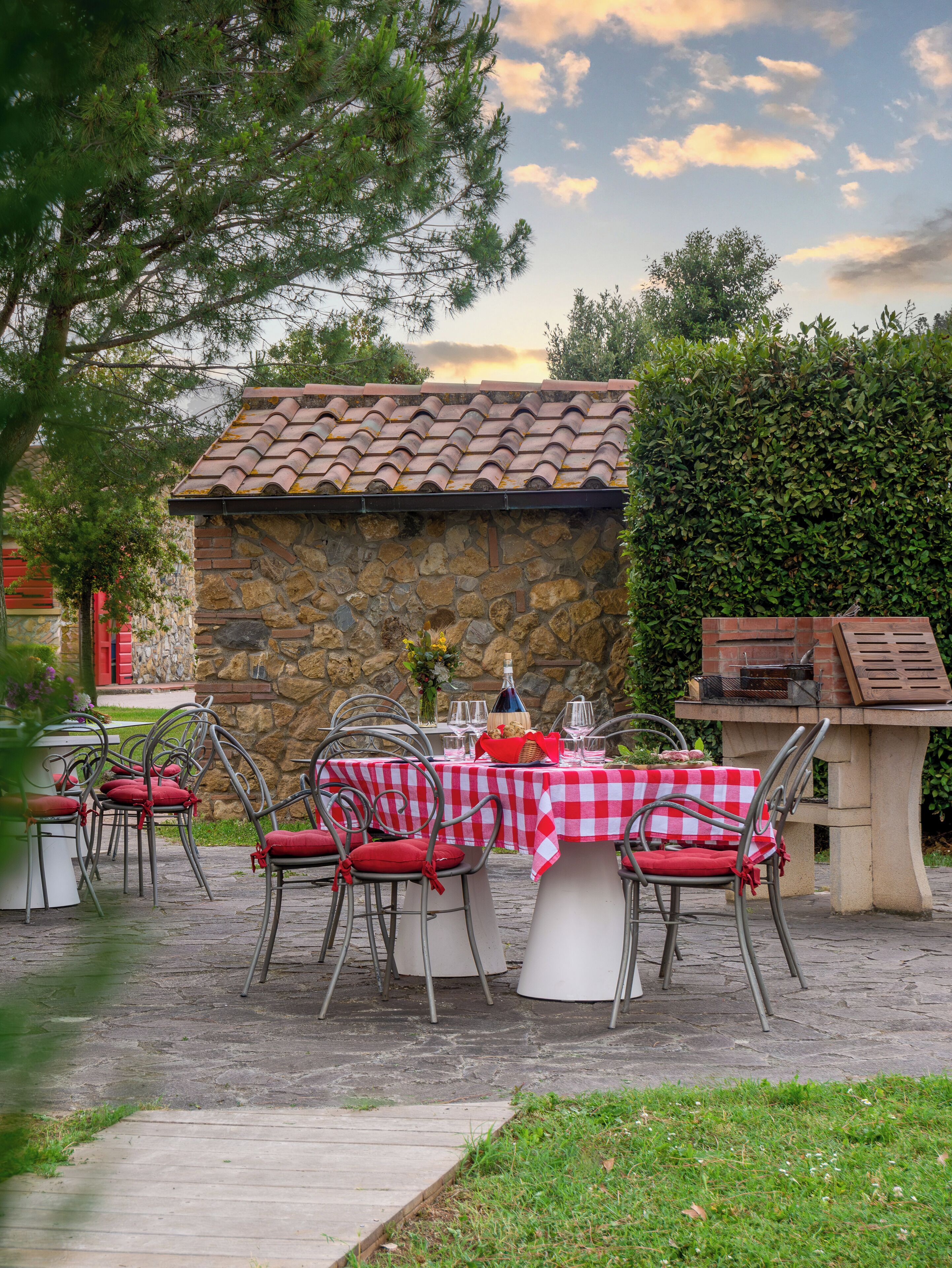 Un patio esterno con pareti in pietra, tetto in tegole e barbecue in mattoni.