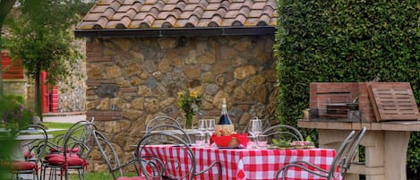 An outdoor patio with stone walls, a tiled roof, and a brick barbecue.