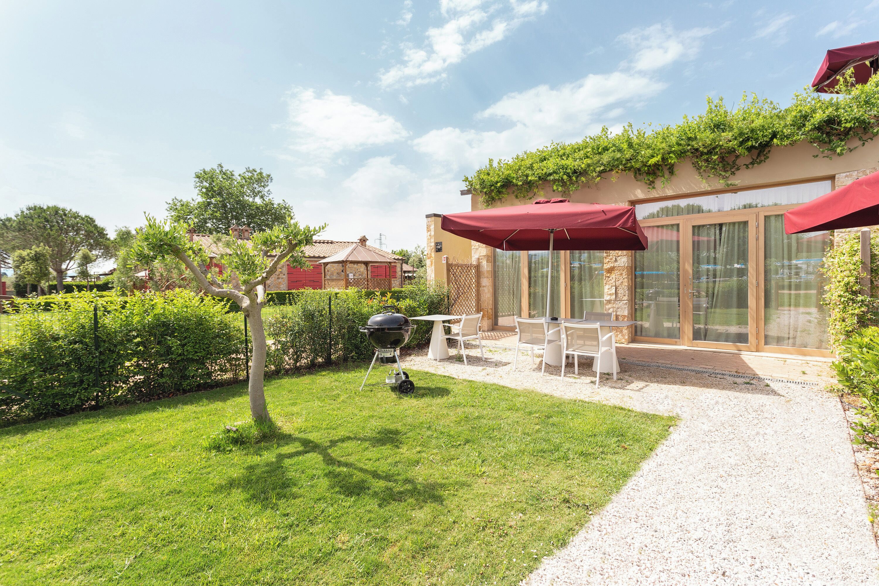 Un patio con una parrilla, mobiliario exterior y vistas a una casa.
