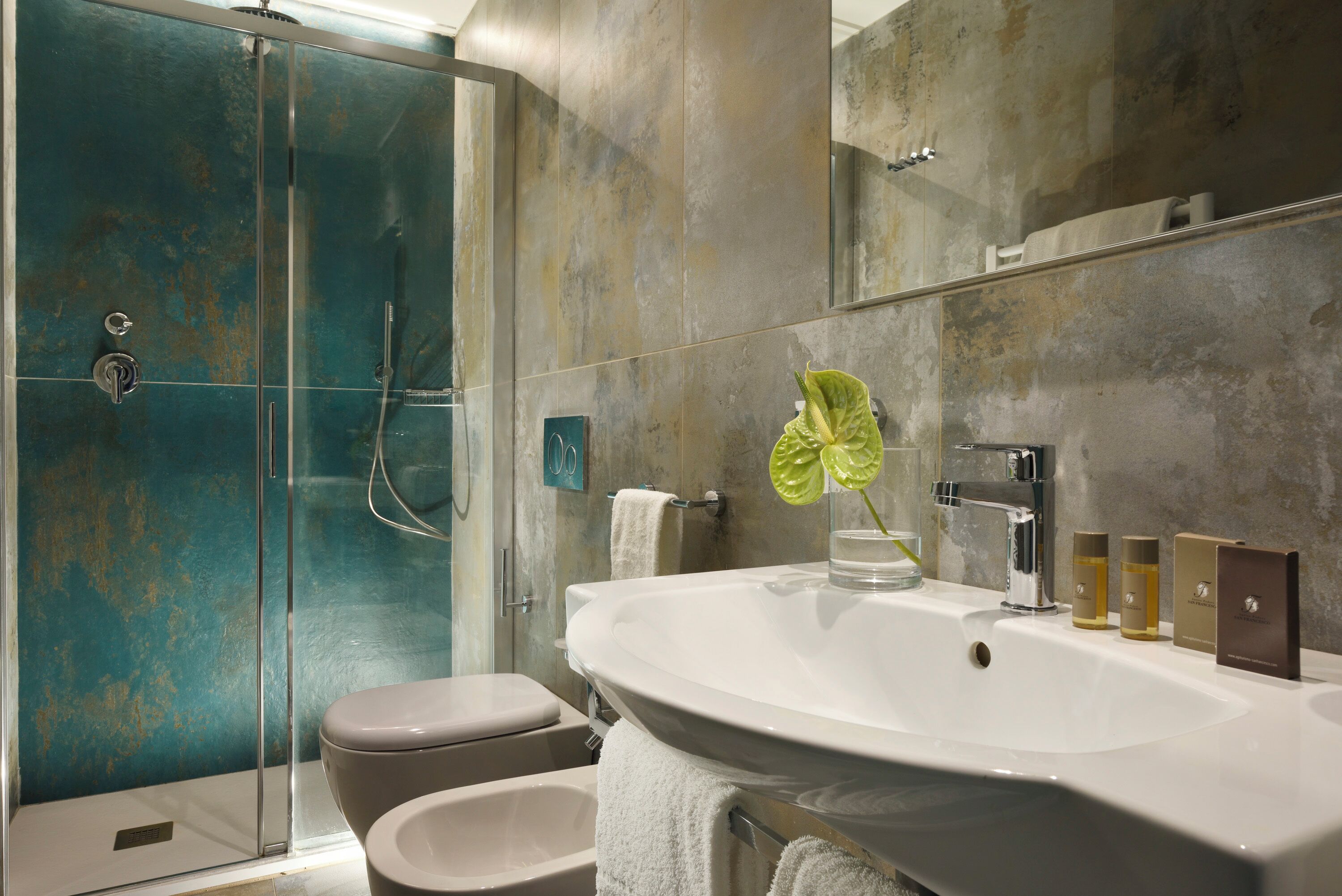 A modern bathroom with a glass-enclosed shower, a large sink, and a mirror.