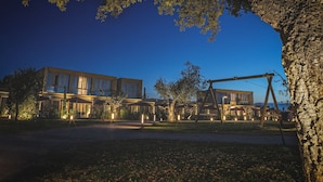 Un hotel moderno con un amplio espacio exterior, que incluye un arenero y senderos bien iluminados.