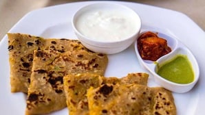A plate with three pieces of flatbread, a bowl of white sauce, and two small bowls of chutney. - Hotel Raghunath (Jammu)