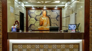 A reception desk with a Buddha statue, a welcome sign, and a security camera. - Hotel Raghunath (Jammu)