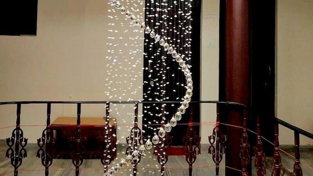 A chandelier with hanging crystals in a modern interior space. - Hotel Raghunath (Jammu)