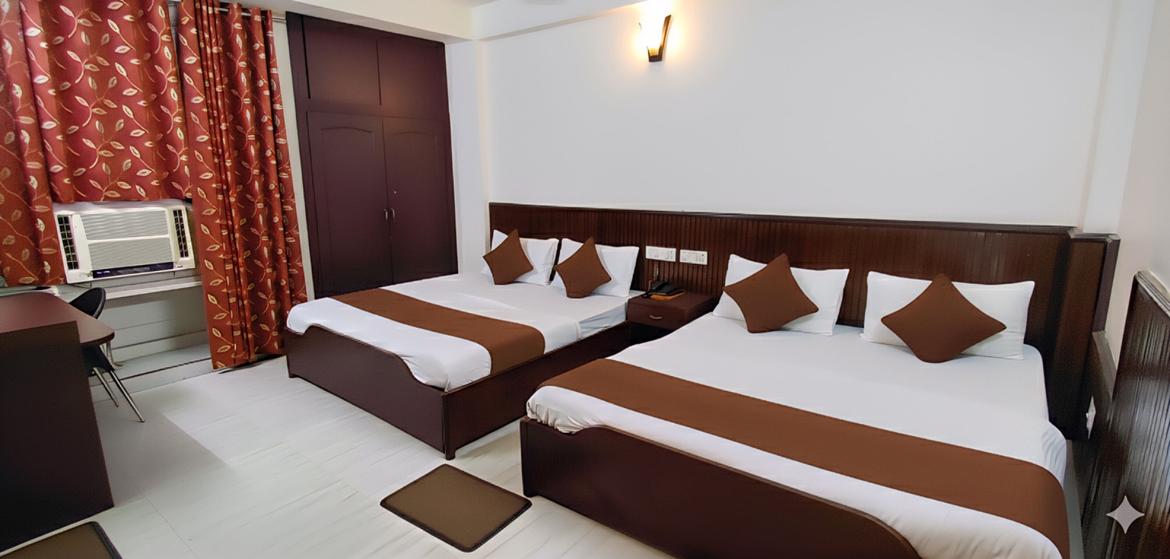 A hotel room with two beds, a desk, and a wardrobe.