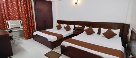 A hotel room with two beds, a desk, and a wardrobe.