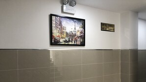 A wall with a framed painting of a city street scene, a sign indicating VIP room numbers, and a ceiling-mounted device. - Happy Homes 95 Le Thi Rieng (Ho Chi Minh City)
