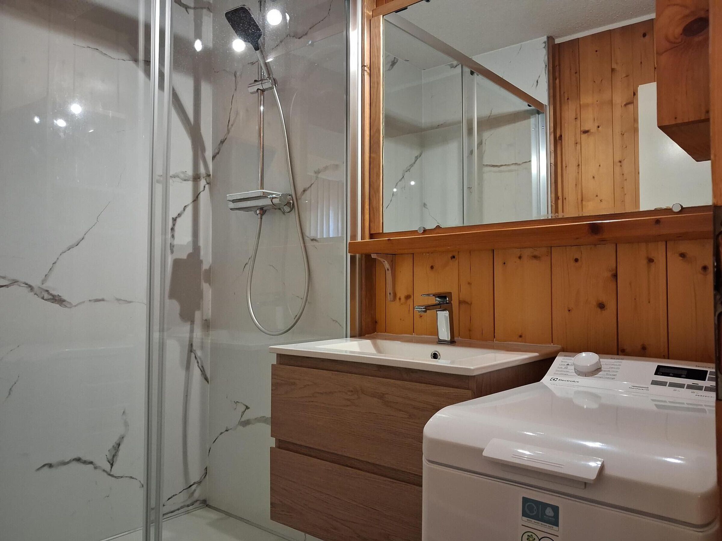 A bathroom with a shower, a sink, and a washing machine.