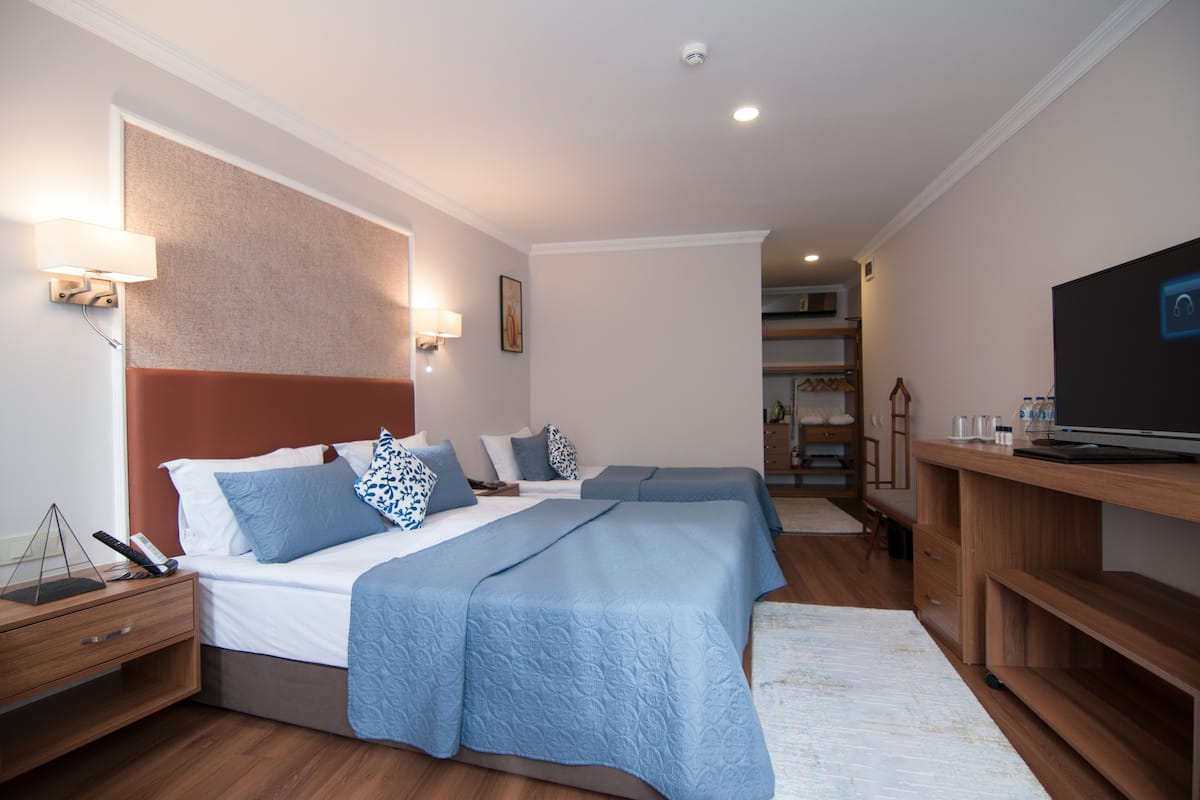 A hotel room with two beds, a TV, a desk, and a nightstand.