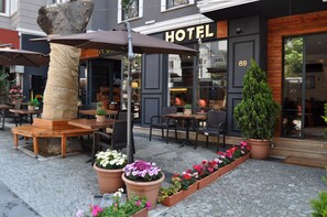 L’extérieur d’un hôtel, avec des espaces de repos en plein air, des plantes en pot et une grande sculpture en forme d’arbre.