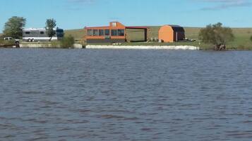 A lakeside property with a large house, a barn, and a trailer.