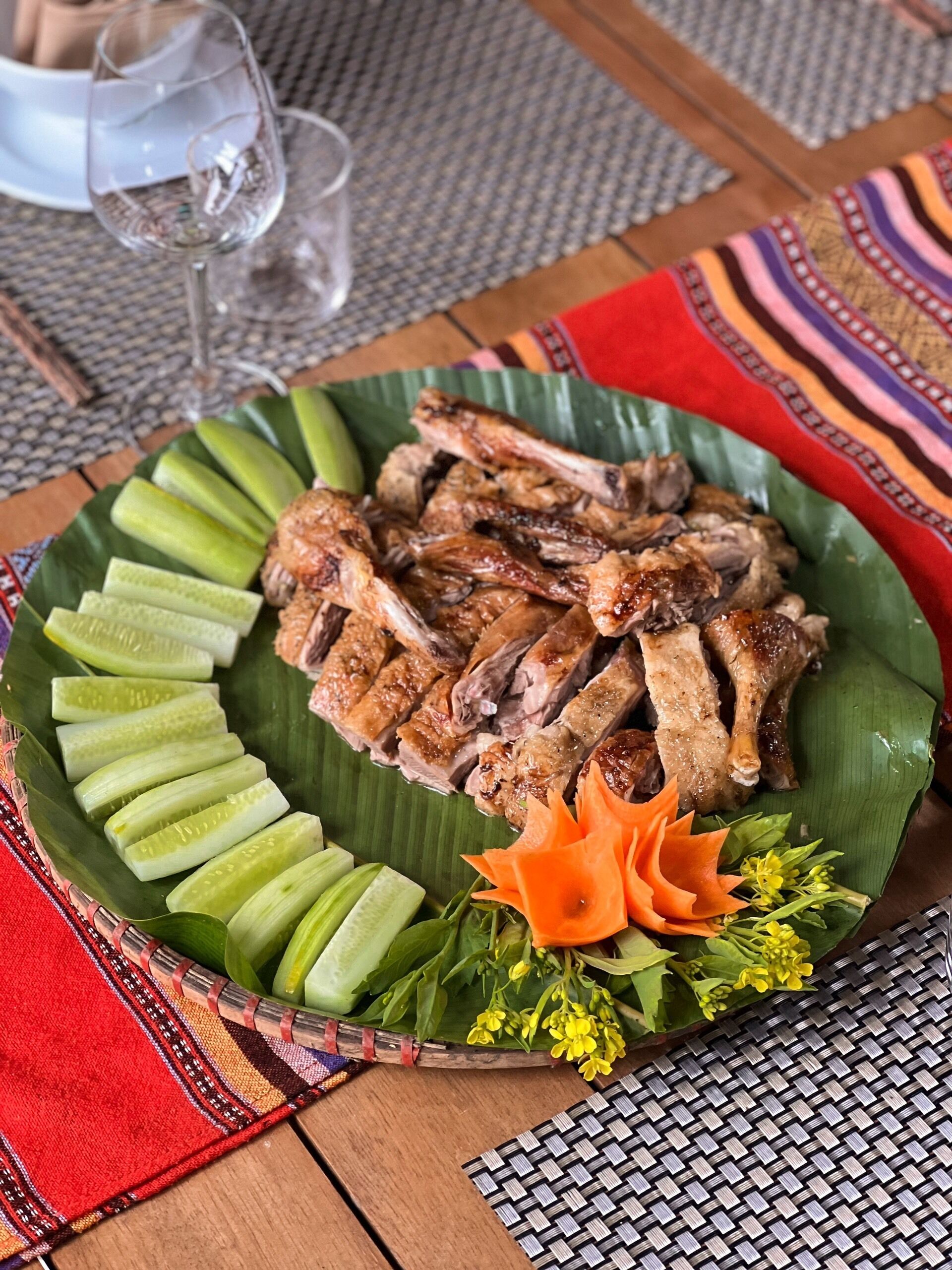 A plate of grilled meat and pickles on a woven placemat.