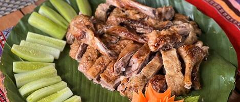 A plate of grilled meat and pickles on a woven placemat.