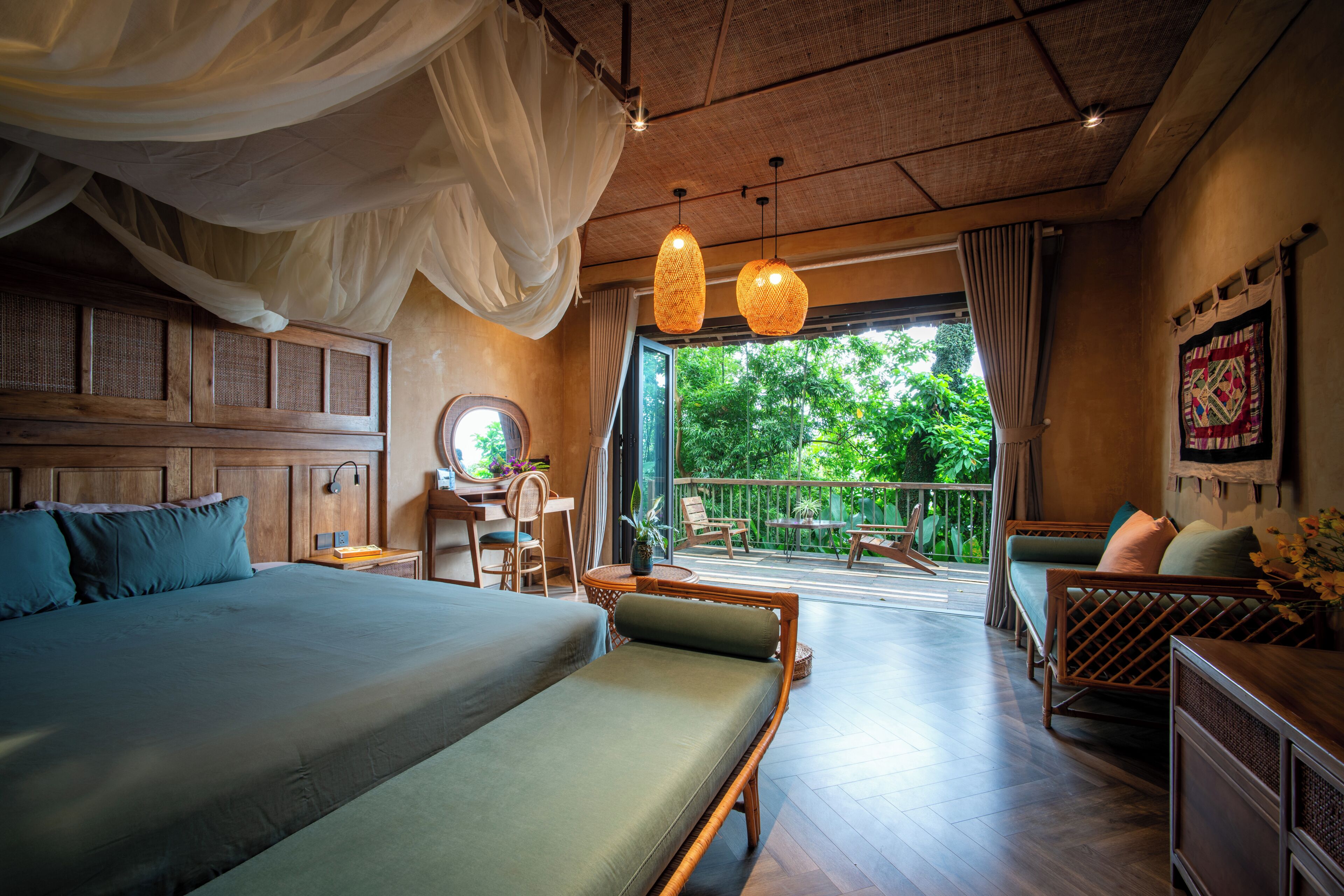 A bedroom with a large bed, a desk, and a view of the outdoors.