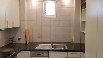A kitchen with white cabinets, a black countertop, a stainless steel sink, and a window above the sink.
