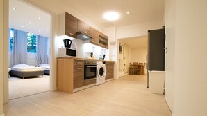 A modern kitchen with a built-in washing machine, wooden cabinets, and a dining area with a table and chairs. - Representative City Villa (Meerbusch)