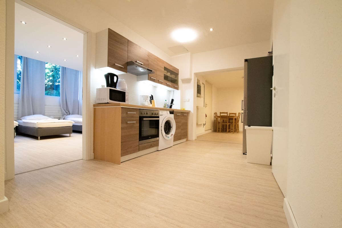 Une cuisine moderne dotée d’un lave-linge encastré, de meubles en bois et d’un coin repas avec une table et des chaises.